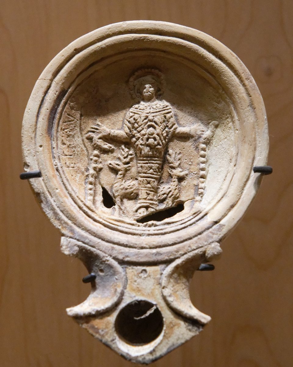 A Roman clay oil lamp stamped with the figure of Artemis of Ephesus standing between two deer