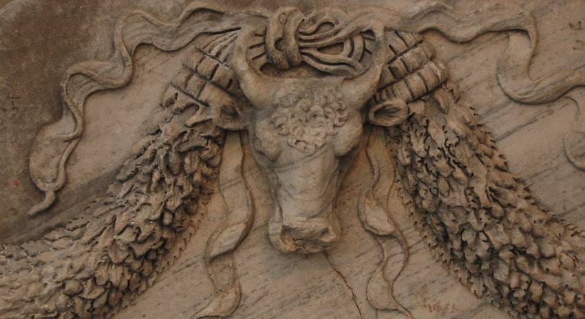 Carved marble relief of a bull’s skull flanked by heavy fruit garlands and trailing ribbons