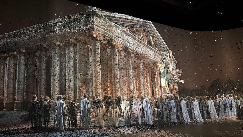 Projected image of the Temple of Artemis with robed figures approaching, filling a dark museum hall