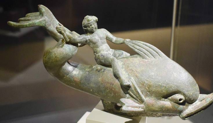 Bronze statuette of Eros riding a dolphin displayed in a case at the Ephesus Museum