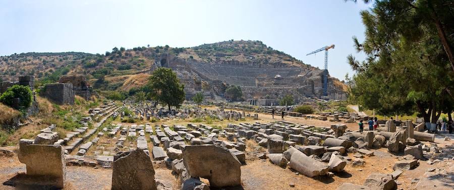 The Great Theater of Ephesus cut into the slope of Mount Pion, seen across a field of fallen marble blocks