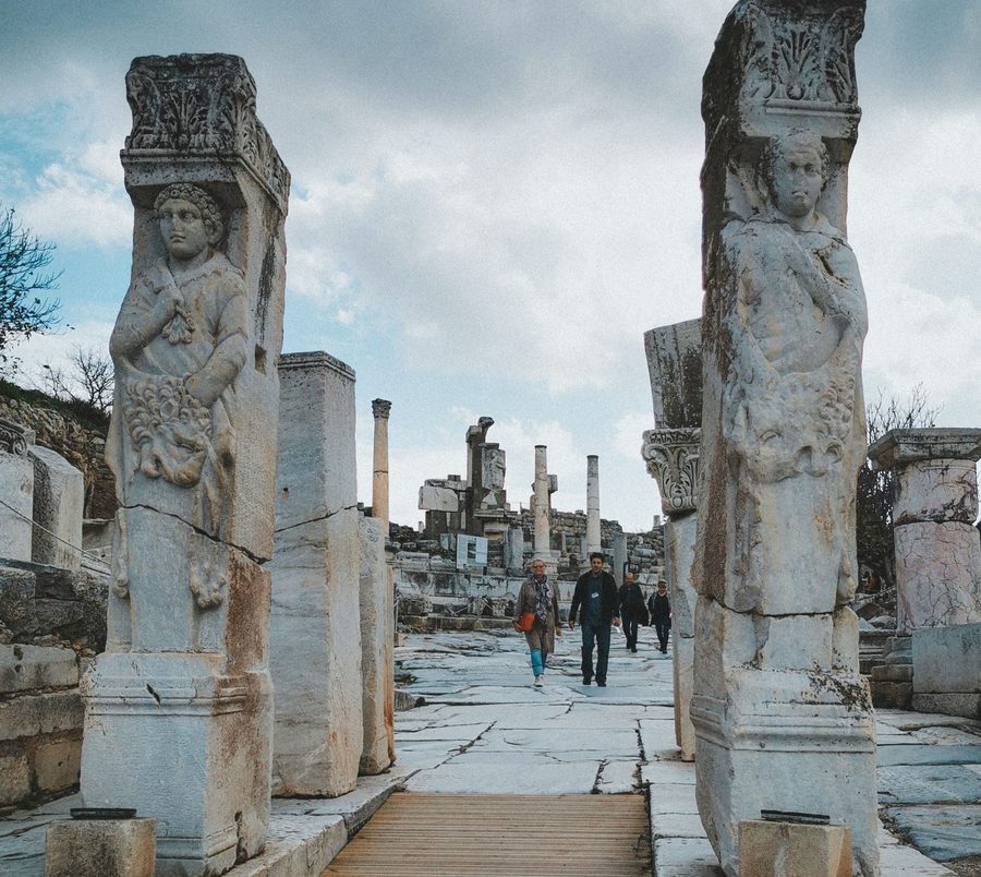 The two carved relief pillars of the Hercules Gate framing the marble paving of Curetes Street at Ephesus