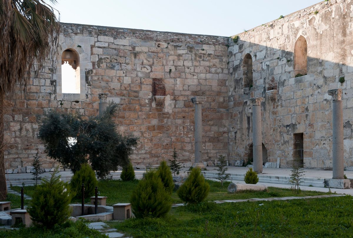 The stone courtyard of the İsa Bey Mosque in Selçuk, with ancient columns and Corinthian capitals standing before its high walls