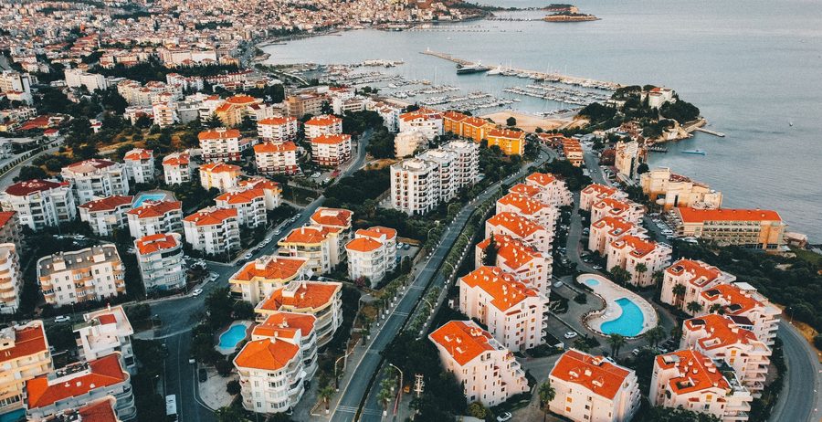 Kuşadası at sunset from the air, with the town wrapped around its bay, the marina, the breakwater and the causeway out to Pigeon Island