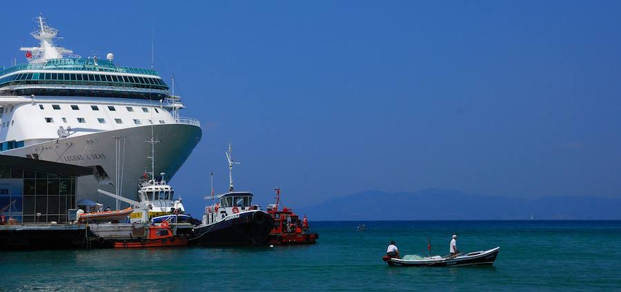 A cruise ship at Kuşadası port and a small fishing boat sharing the same blue water