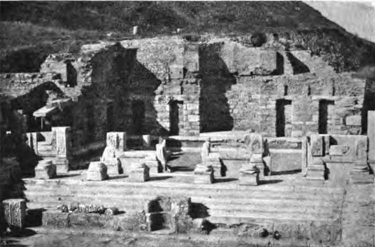 Early twentieth-century black-and-white photograph of the excavated Library of Celsus: the wide staircase, pedestals on the podium and the ruined walls of the hall, with no façade standing