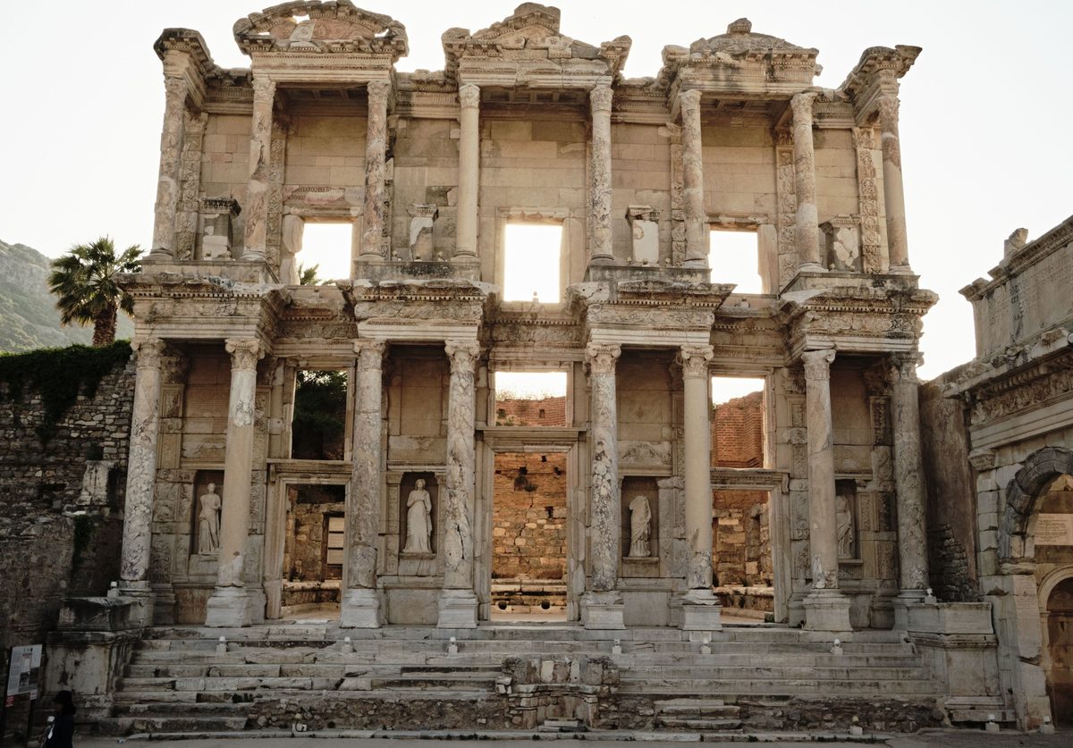 The two-story marble facade of the Library of Celsus at Ephesus in late backlight, its statues standing in the lower niches