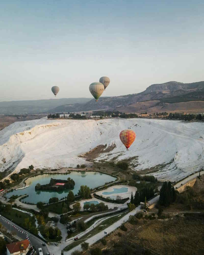 Hot air balloons drifting over the white travertines of Pamukkale
