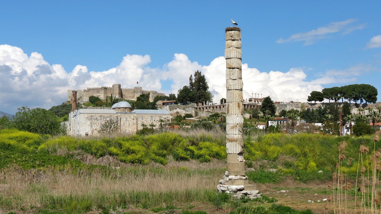 The single re-erected column of the Temple of Artemis at Selçuk with a stork standing on its nest on top, the İsa Bey Mosque and Ayasuluk Fortress behind
