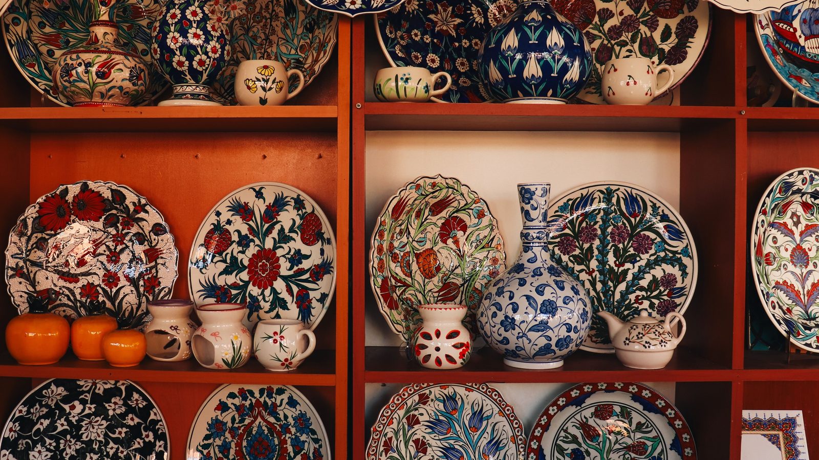 Shelves of hand-painted İznik-style plates, vases, cups and a teapot decorated with tulips, carnations and cobalt-blue flowers